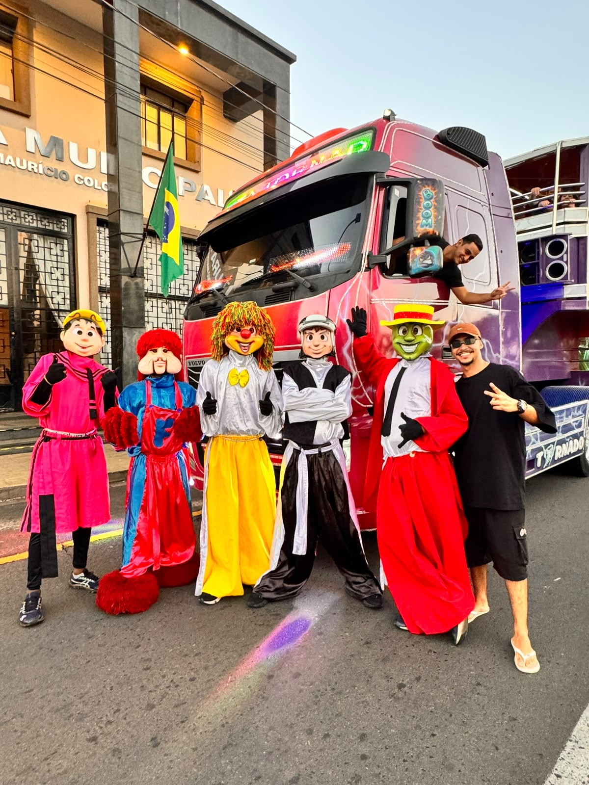 Personagens fantasiados ao lado da Carreta Tornado na rua