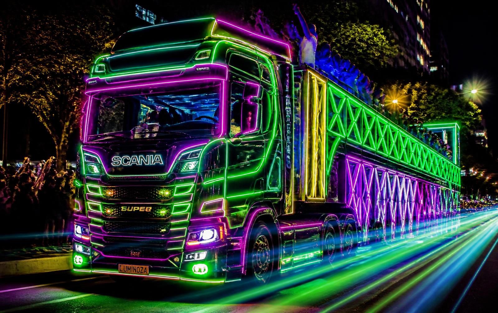 Carreta Scania iluminada com luzes neon em uma avenida à noite